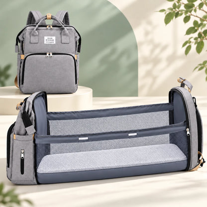 The same gray diaper backpack shown closed and opened into a fold-out changing space with mesh sides and a flat pad. Two configurations of one product.
